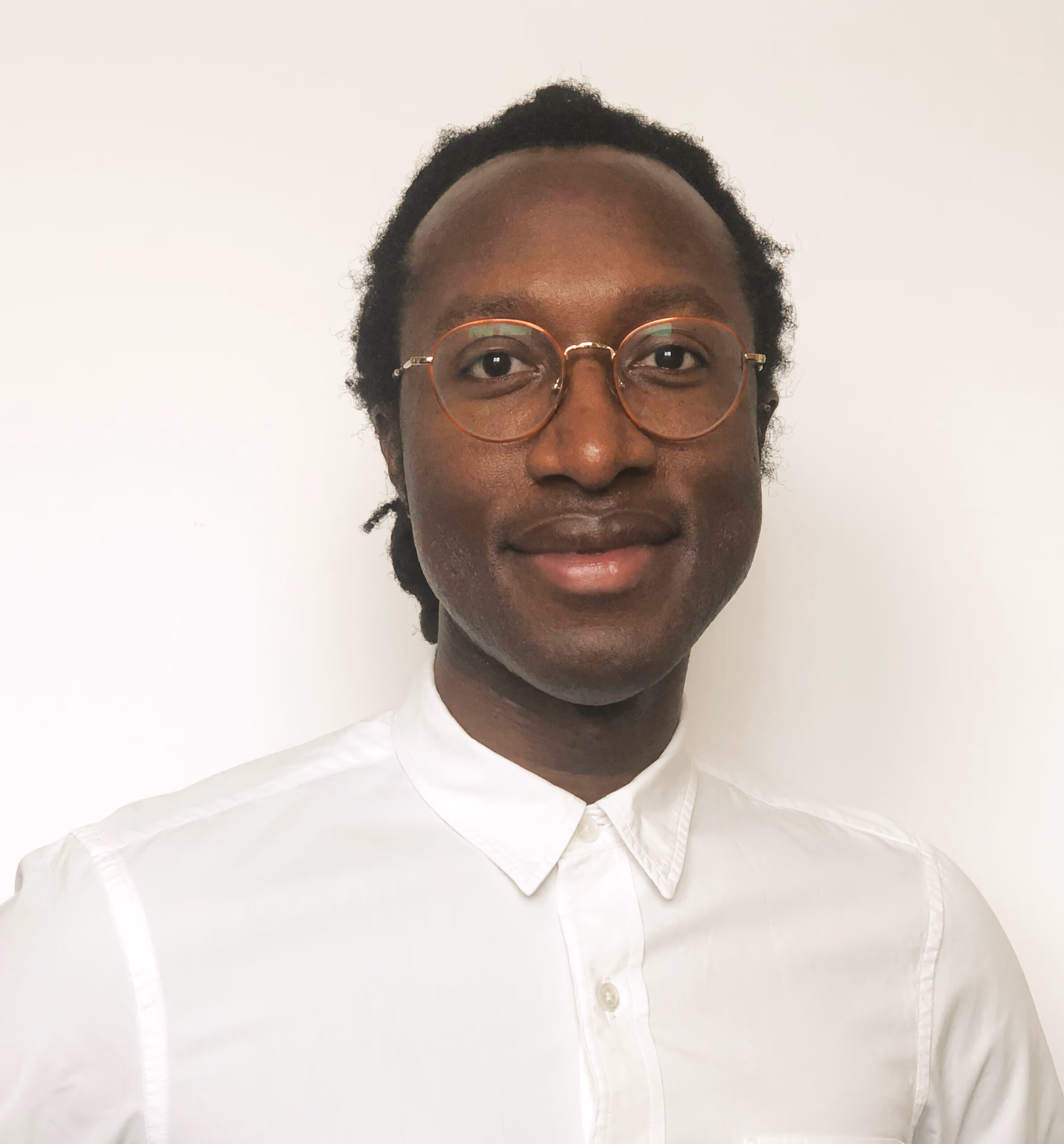 Evan Larbi, smiling, in a white shirt and glasses